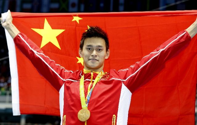 2016年8月8日，在里约奥运会男子200米自由泳颁奖仪式后，孙杨举起国旗庆祝，新华社记者丁旭摄