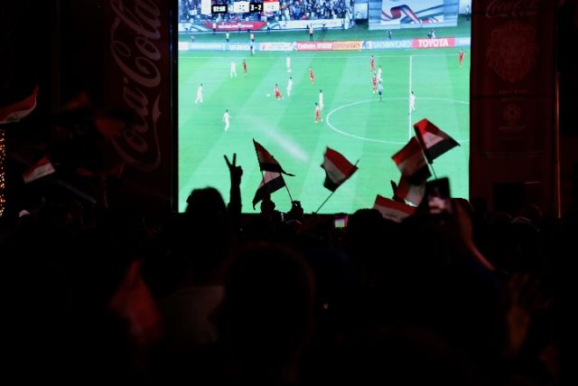 1月8日，伊拉克球迷在首都巴格达曼苏尔区一家商场外搭起的大屏幕前观看亚洲杯球赛直播。哈利勒·达伍德摄