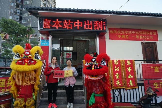 图为南宁市福彩中心工作人员为中奖投注站业主(右)颁发奖励金和牌匾