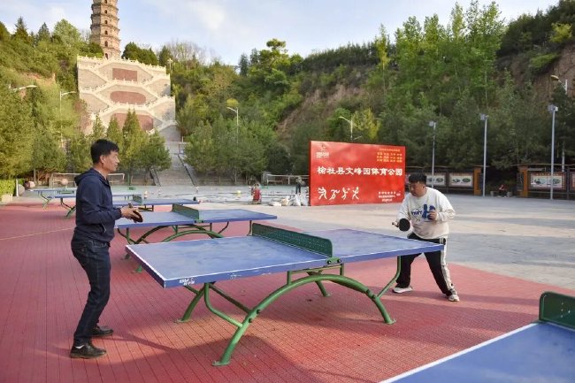 老伙计们正在乒乓球台前切磋球技