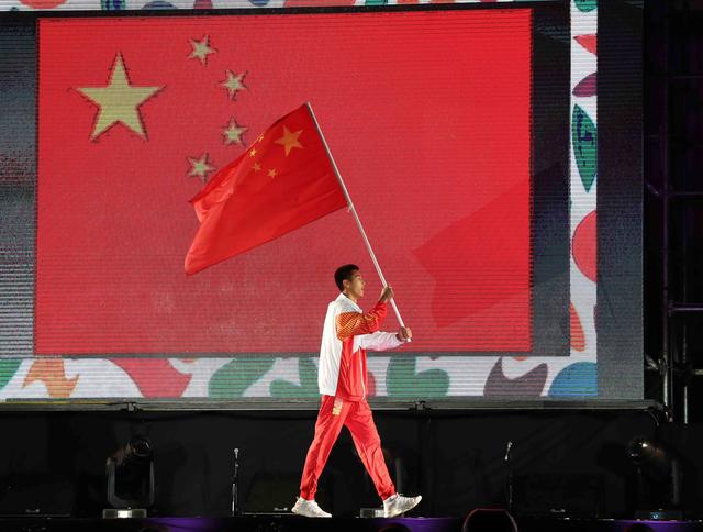 中国代表团旗手王云章在开幕式上高举国旗入场