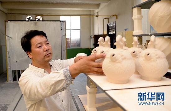 崔涛在摆放准备入窑烧制的耀州窑青釉剔花倒装壶(7月10日摄)。