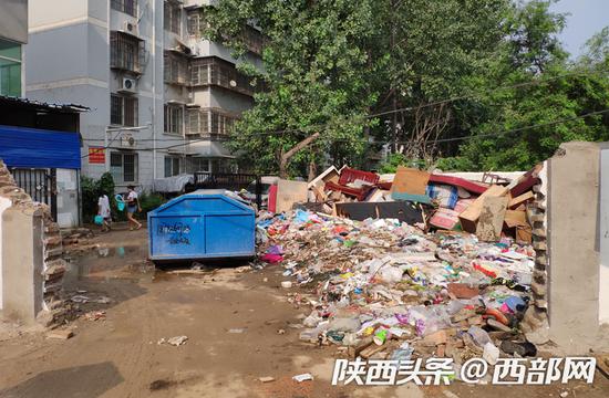 西门外右边围墙下堆满了生活垃圾和一些废弃家具。
