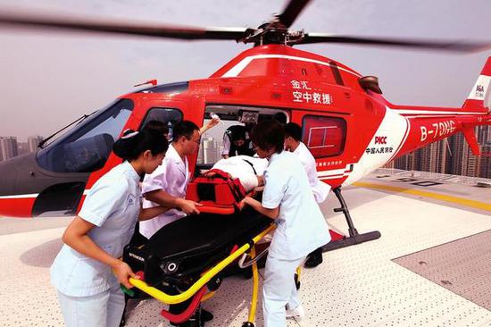 医护人员将患者抬下直升机 本报记者马昭摄