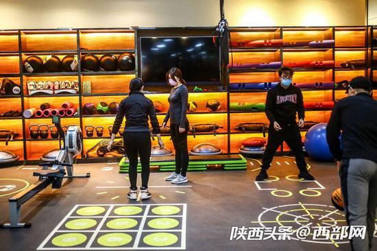 西安部分健身房开始复工,市民戴口罩“撸铁”健身。