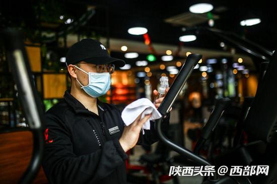西安部分健身房开始复工,市民戴口罩“撸铁”健身。
