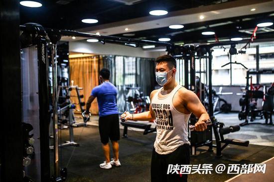 西安部分健身房开始复工,市民戴口罩“撸铁”健身。