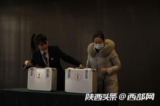 购房家庭代表上台检查密码箱密封情况并选择一个密码箱。