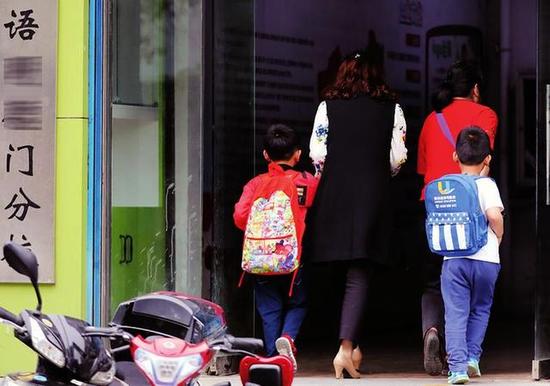 家长领着孩子走进补习学校 本报记者马昭摄