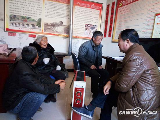 薛毅（右一）生前在村委會和村民們在一起。