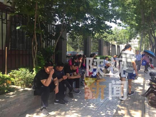 (图为在摇号现场外焦急等待的家长)