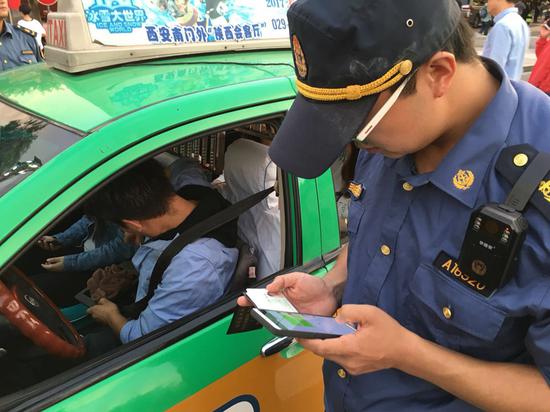 工作人员正在检查出租车司机的证件信息。