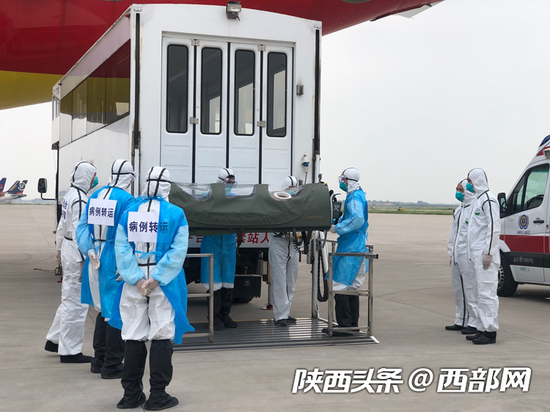 升降平台车进入隔离警戒区,将负压担架和4名转运病例组人员从后舱门送入客舱,帮助疑似病例平躺在担架。