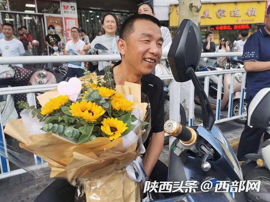 安康中学考点门前,不少爸爸也手捧鲜花,迎接顺利完成考试的孩子。
