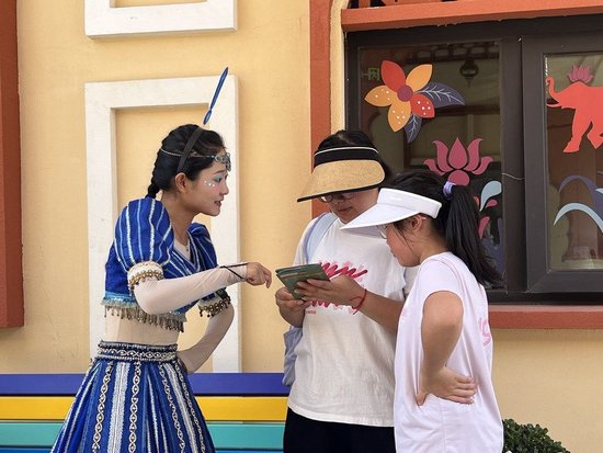 游客在丝路文化主题乐园丝路欢乐世界与景区工作人员交流（8月2日摄）。新华社记者 蔡馨逸 摄