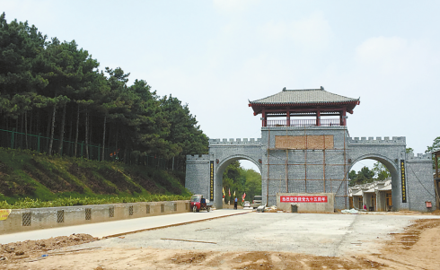 仿古牌楼前大块的水泥地与旁边未被破坏的油松林形成鲜明对比。