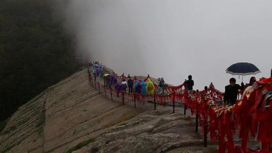 游客在细雨中登顶华山西峰莲花峰。