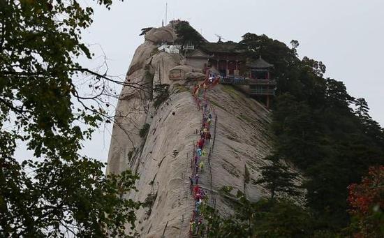 游客在细雨中登顶华山西峰莲花峰。