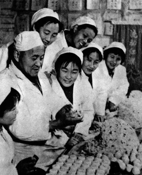 西安市东厅门食品厂技师王如林向青年工人传授花式糕点的制作技术。资料照片