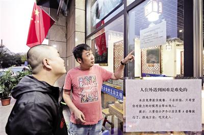 店主张小军向路人介绍提供“爱心餐”的初衷 本报记者 王晓峰 摄