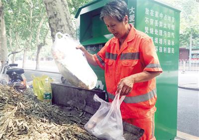 保洁员从爱心捐衣箱里掏出垃圾 记者 代泽均 摄