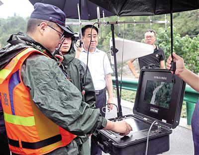 8月7日，在洛南县石门镇242国道旁，消防员通过无人机传回的画面察看灾情。