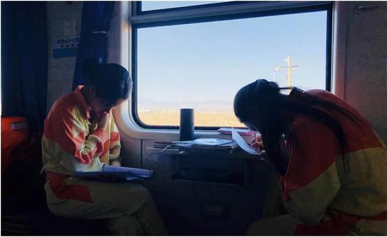 在前往目的地的火车上，学生完成一天的课程作业