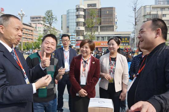 嘉宾在镇巴旅游产品展台前，品尝竹筒酒赞不绝口