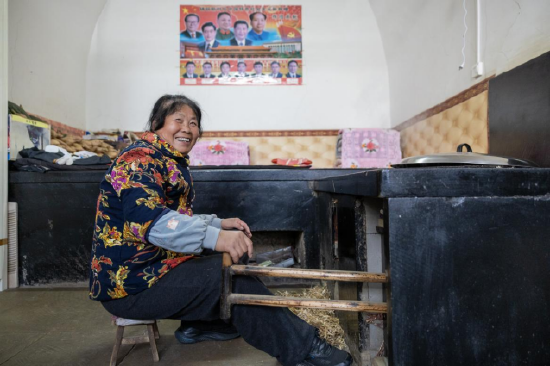 图为雷兴芳老人拉着风箱，讲述着生活的变迁