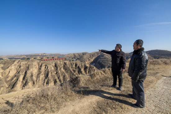 图为高西沟村党支部副书记高利东和村民一起瞭望远处的光伏板