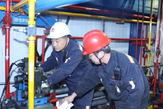 图为许伟（左）与工友专注检修设备