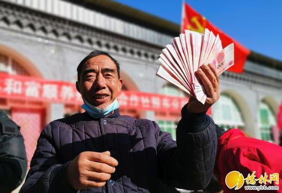 村民李鳳雄開心地展示拿到手的分紅 謝妮妮攝