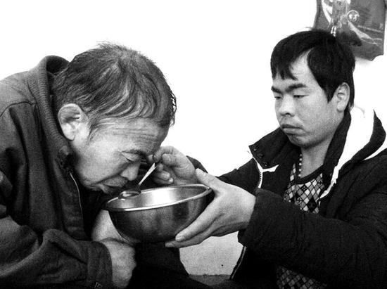 父親生活無法自理，王旭光耐心地給父親喂水喂飯