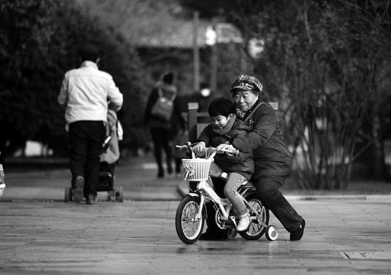 在环城公园里，老人陪孩子骑车    本报记者代泽均摄
