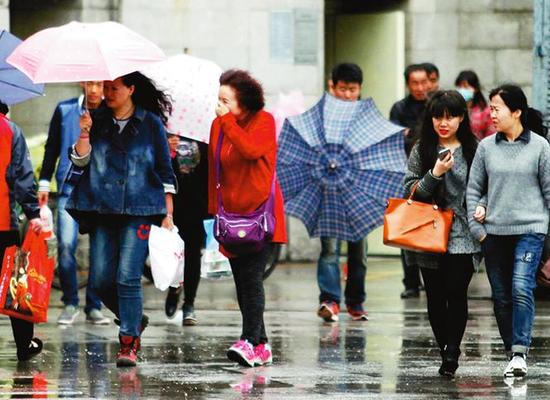 風(fēng)雨中出行的市民 本報(bào)記者代澤均攝