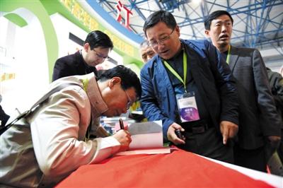 昨日，國(guó)展壹號(hào)土豬展位前，陸步軒在簽名售書。新京報(bào)記者 浦峰 攝