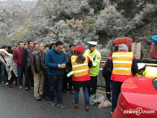安康交警為高速路上滯留司乘人員發(fā)放食物。