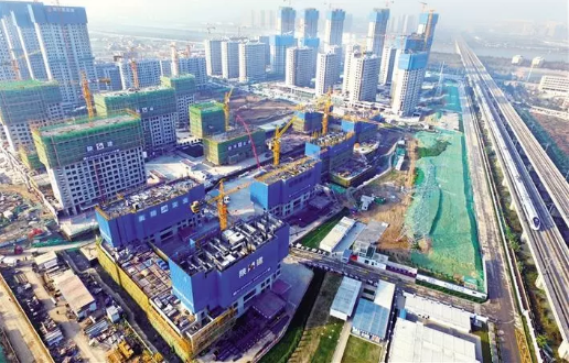11月19日,一列高速列车驶过正在建设中的西安全运村。西安全运村为2021年全运会的配套项目,其中十五栋楼将作为运动员的公寓在赛事期间使用。该村一至六地块(建筑)由陕建集团承建。陕西日报记者 袁景智摄