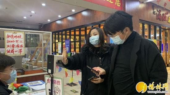 图为商场入口处,市民正在测量体温。杨荣 摄
