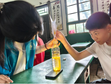 图为实践队员指导学生完成“流星雨”科学实验