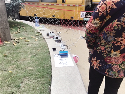 居民在應(yīng)急發(fā)電車前給手機充電