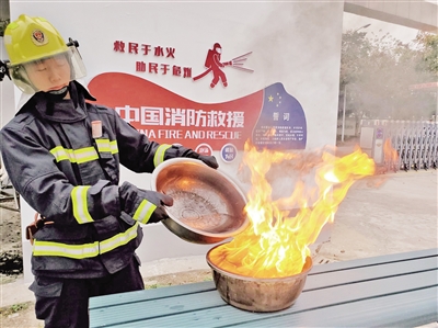 消防员演示水灭油锅的危险性 首席记者 葛兰 摄