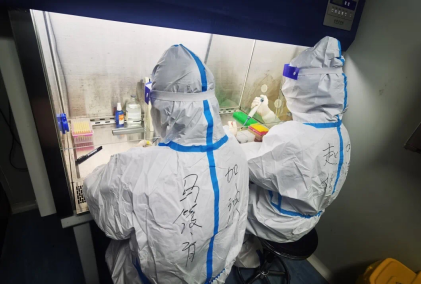 标本制备室里，身穿防护服的检验员从采样管中吸取一定量的样本