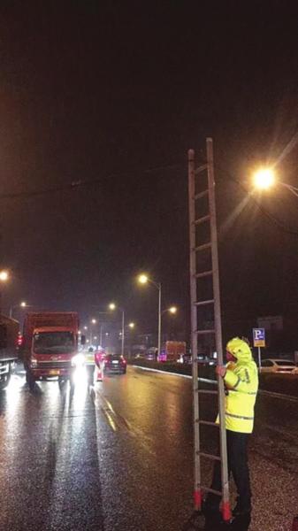 常熟交警大队尚湖中队民警和辅警扶着长梯,轮流在雷雨中架起坠地电缆线保道路通畅(照片为网友提供)