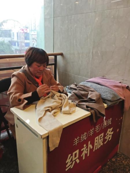 随着气温下降,织补生意也火爆起来。图为织补师正在修复一件羊绒衫。 □小圆 摄
