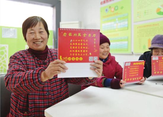 社区居民展示刚收到的《老苏州美食台历》。 □徐佳艳 摄