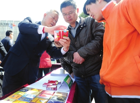 昨天举行的“3·15”咨询服务活动现场,工作人员在向市民传授辨别真假香烟的方法。