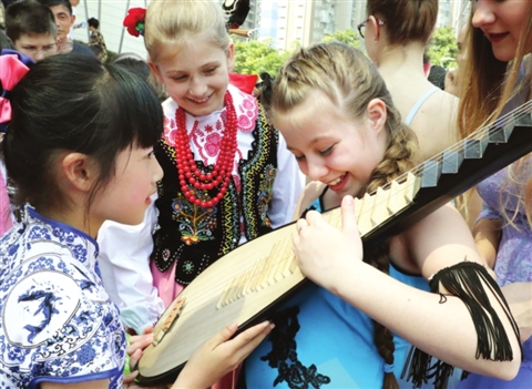 近日的国粹系列活动上,身穿青花瓷纹样旗袍的苏州小学生在教波兰小姐姐弹奏琵琶。 □记者 华雪根 摄