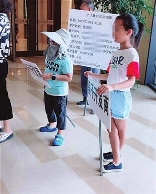 两个孩子在售楼处举牌(应先生供图)