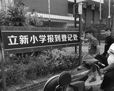 勤惜小学北门处挂出的“立新小学报到登记处”牌子,家长们在此焦急守候。